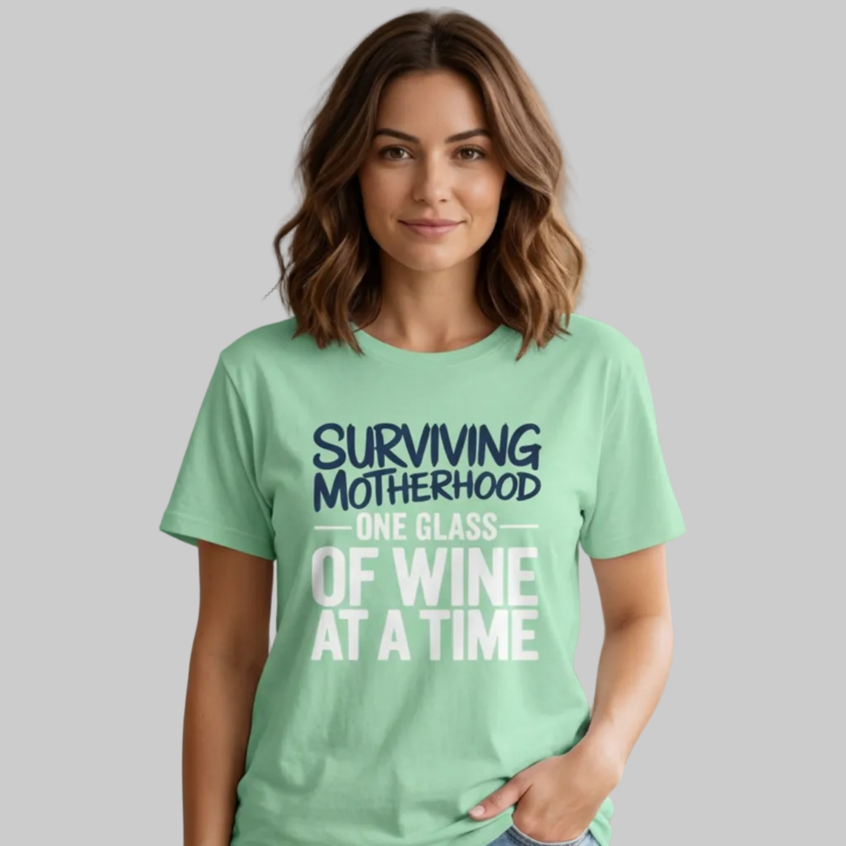 Woman wearing a light green t-shirt with the phrase 'Surviving Motherhood One Glass of Wine at a Time' funny Mother's day, beach vacation, spring break design