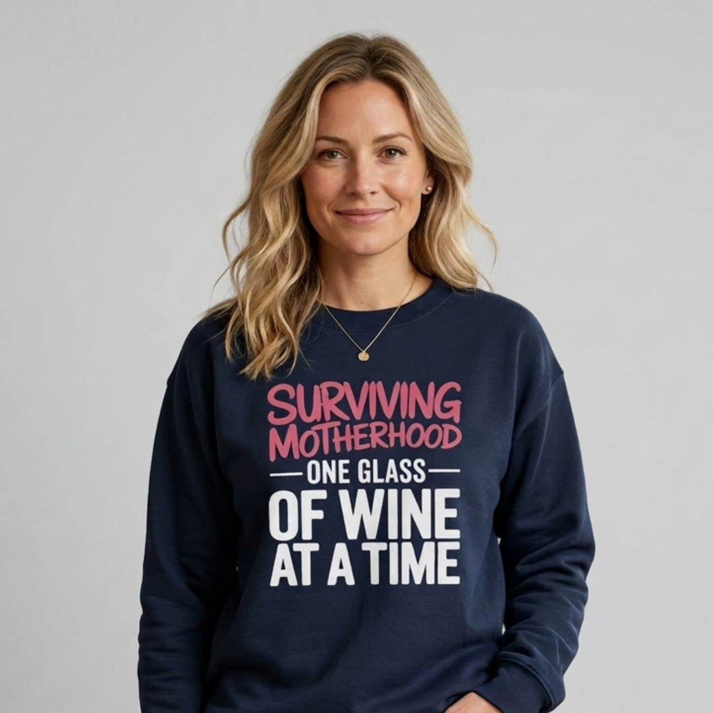 Woman wearing a navy sweatshirt with the phrase 'Surviving Motherhood One Glass of Wine at a Time' funny mother's day, mom life, girls trip design
