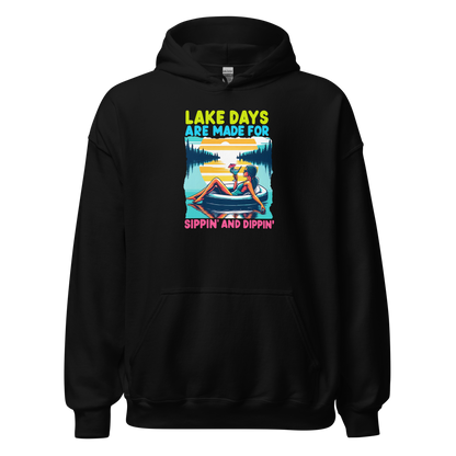 Hoodie with "Lake Days Are Made for Sipping and Dipping," showing a woman on a tube float with a cocktail, lake and sunset scene.