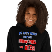 Woman wearing "I'm Just Here for the Fireworks and Beer" cozy black hoodie with a joyful smile.