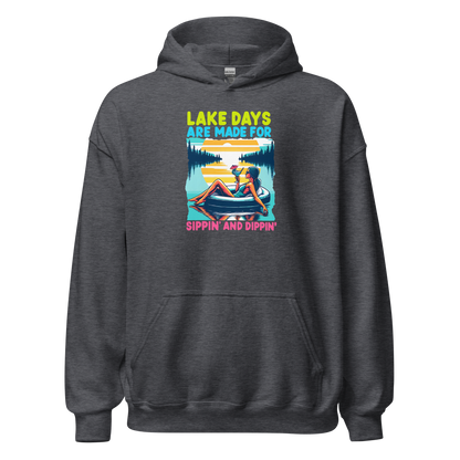 Hoodie with "Lake Days Are Made for Sipping and Dipping," showing a woman on a tube float with a cocktail, lake and sunset scene.