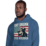 Hoodie with Day Drunk for America text, silhouette of a man drinking a bottle of beer, and distressed American flag background. Perfect for 4th of July.