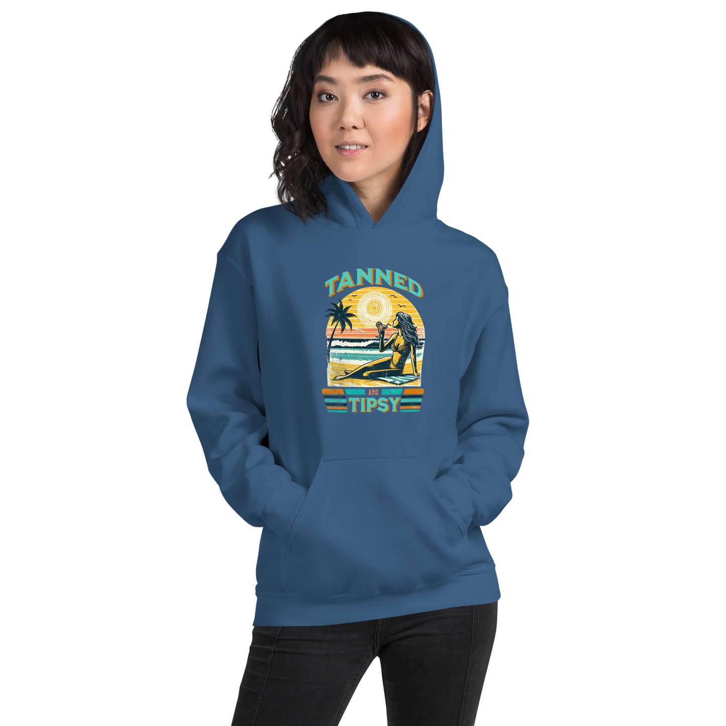 Woman on beach at sunset in our 'Tanned and Tipsy' hoodie, combining vintage charm with beach drinking fun, ideal for cooler evenings.