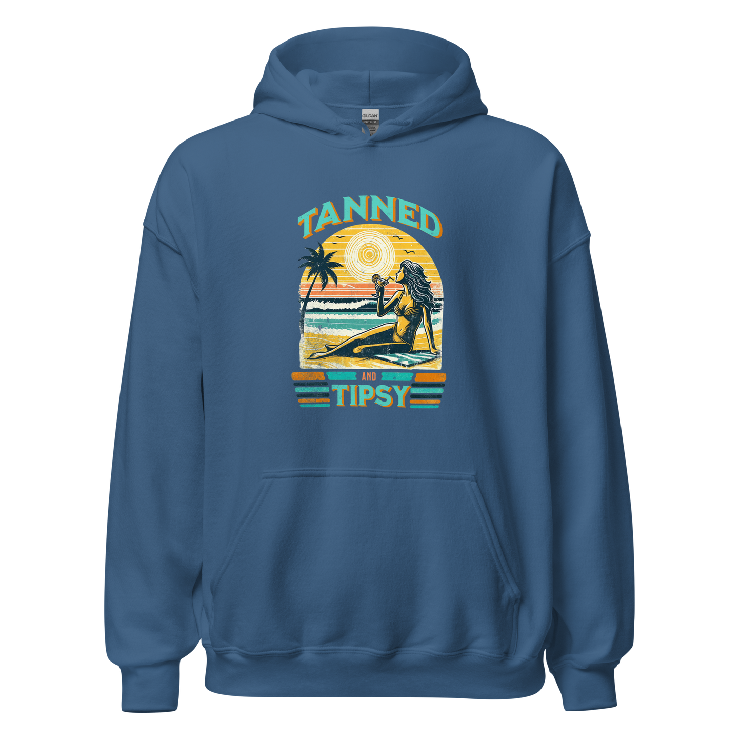 Woman on beach at sunset in our 'Tanned and Tipsy' hoodie, combining vintage charm with beach drinking fun, ideal for cooler evenings.