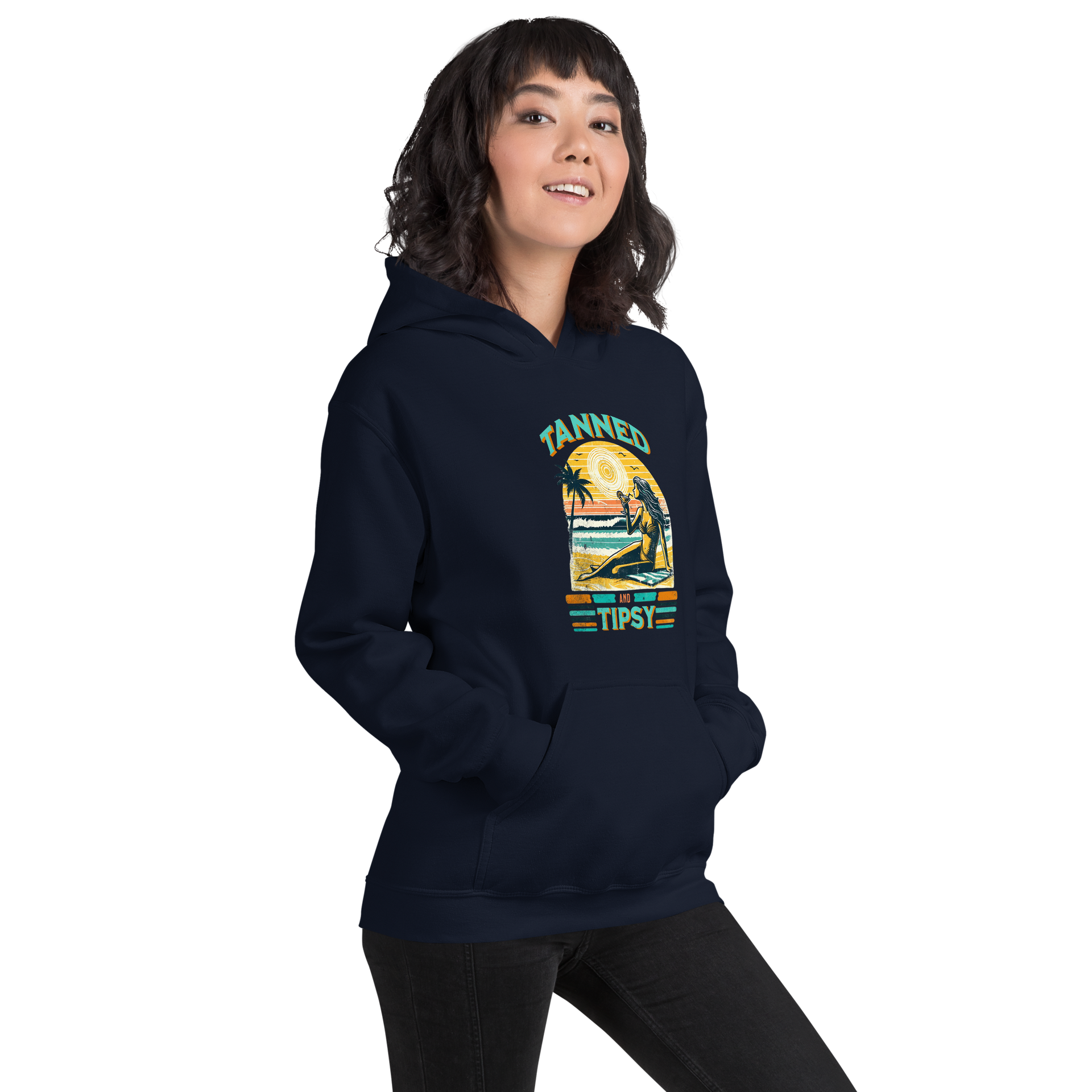 Woman on beach at sunset in our 'Tanned and Tipsy' hoodie, combining vintage charm with beach drinking fun, ideal for cooler evenings.