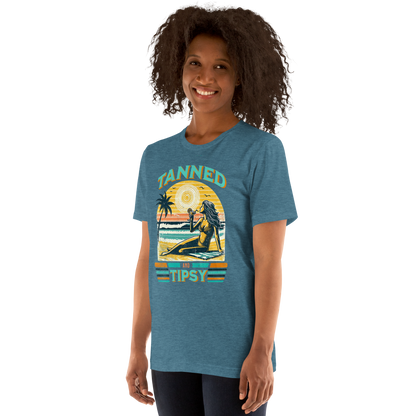 Vintage-inspired 'Tanned and Tipsy' tee with a woman sipping a cocktail on a beach at sunset, perfect for beach drinking and summer parties.