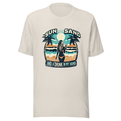 Woman with cocktail on beach on 'Sun, Sand, and a Drink in My Hand' tee, showcasing ocean and sun background