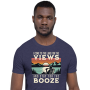 Tee showing "I Come to the Lake for the Views and Stay for the Booze," with a man in a beach chair, lake, and retro sunset.