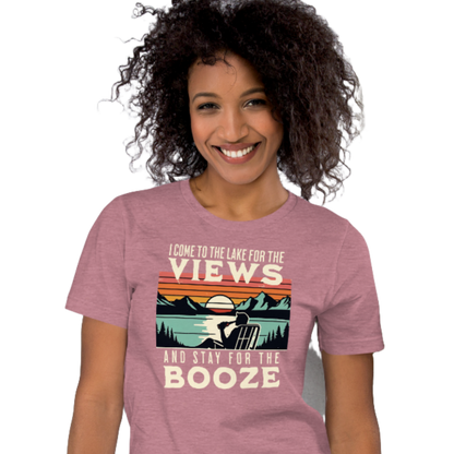 Tee showing "I Come to the Lake for the Views and Stay for the Booze," with a man in a beach chair, lake, and retro sunset.
