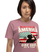 T-shirt with Celebrating America One Shot at a Time text, silhouette of a man drinking a shot, and distressed American flag background. Perfect for 4th of July.