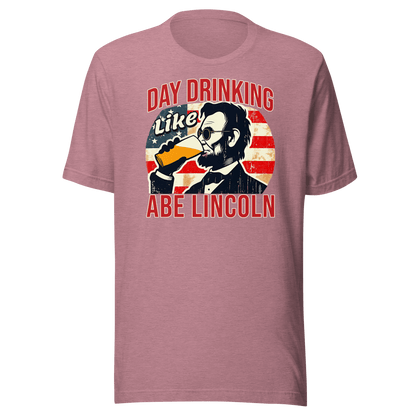 T-shirt with Day Drinking Like Abe Lincoln text, image of Abe Lincoln drinking a glass of beer, and distressed American flag background. Perfect for 4th of July.