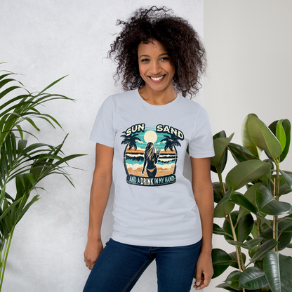 Woman with cocktail on beach on 'Sun, Sand, and a Drink in My Hand' tee, showcasing ocean and sun background