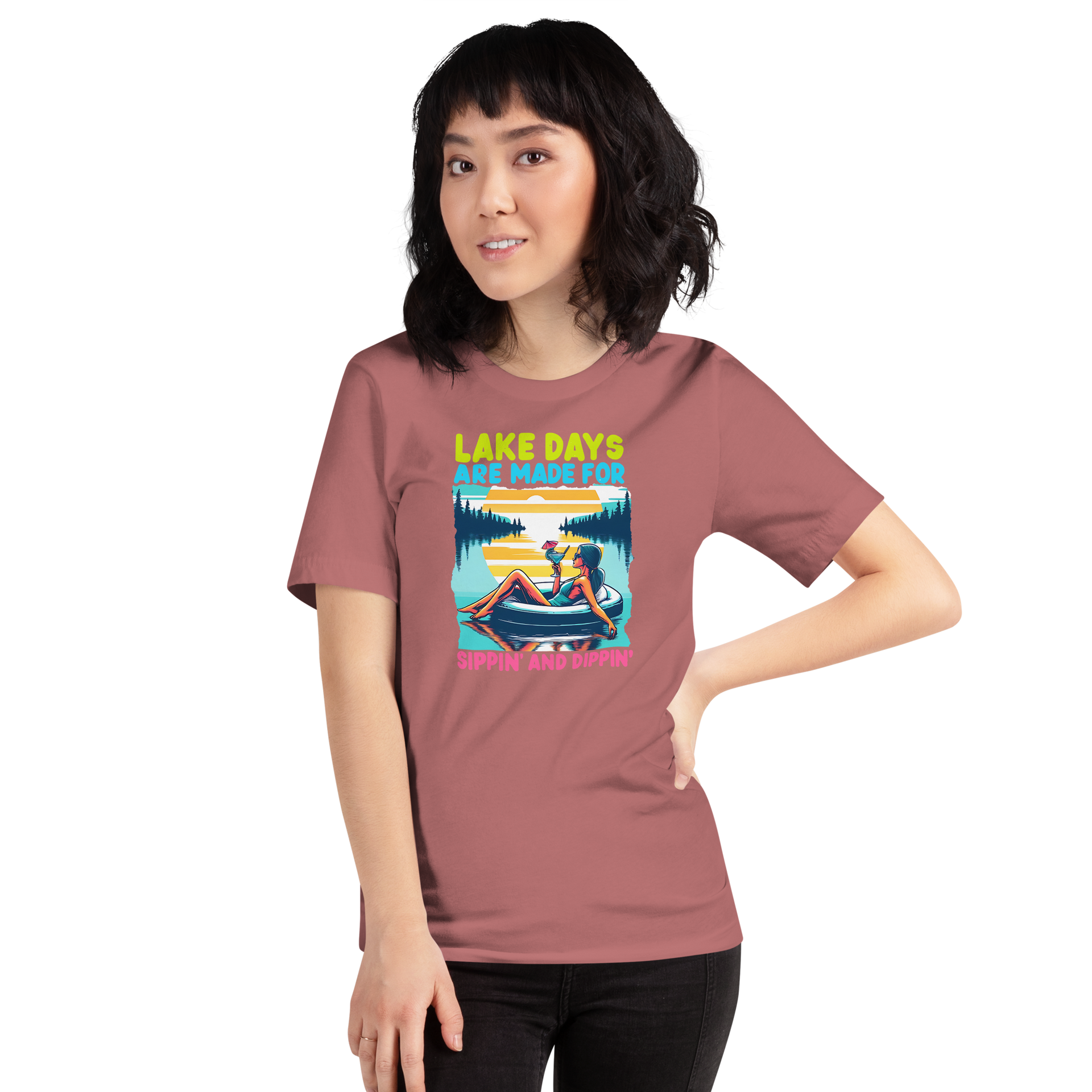 Tee with "Lake Days Are Made for Sipping and Dipping," featuring a woman on a tube float with a cocktail, lake and sunset backdrop.