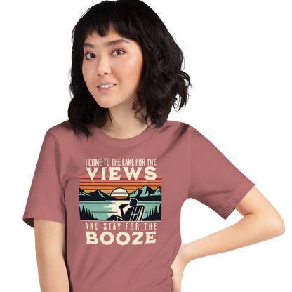 Tee showing "I Come to the Lake for the Views and Stay for the Booze," with a man in a beach chair, lake, and retro sunset.