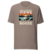 Tee showing "I Come to the Lake for the Views and Stay for the Booze," with a man in a beach chair, lake, and retro sunset.