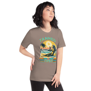 Vintage-inspired 'Tanned and Tipsy' tee with a woman sipping a cocktail on a beach at sunset, perfect for beach drinking and summer parties.