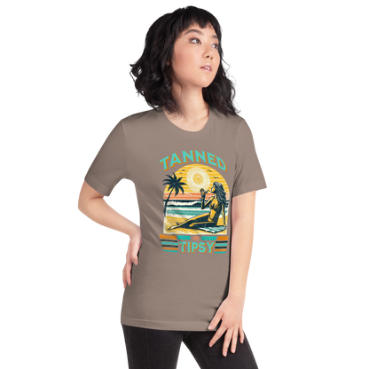 Vintage-inspired 'Tanned and Tipsy' tee with a woman sipping a cocktail on a beach at sunset, perfect for beach drinking and summer parties.