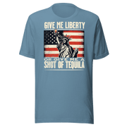 T-shirt with Give Me Liberty or Give Me a Shot of Tequila text, Statue of Liberty holding a shot glass, and distressed American flag background. Perfect for 4th of July.