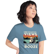 Tee showing "I Come to the Lake for the Views and Stay for the Booze," with a man in a beach chair, lake, and retro sunset.