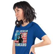 4th of July T-shirt with '100% American Drunkard' text, man drinking a bottle of beer wearing a trucker hat, and distressed American flag background