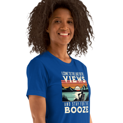 Tee showing "I Come to the Lake for the Views and Stay for the Booze," with a man in a beach chair, lake, and retro sunset.