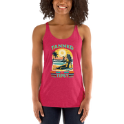 Retro 'Tanned and Tipsy' racerback tank with a woman enjoying a sunset cocktail on the beach, ideal for summer beach parties and day drinking.