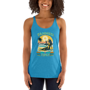 Retro 'Tanned and Tipsy' racerback tank with a woman enjoying a sunset cocktail on the beach, ideal for summer beach parties and day drinking.