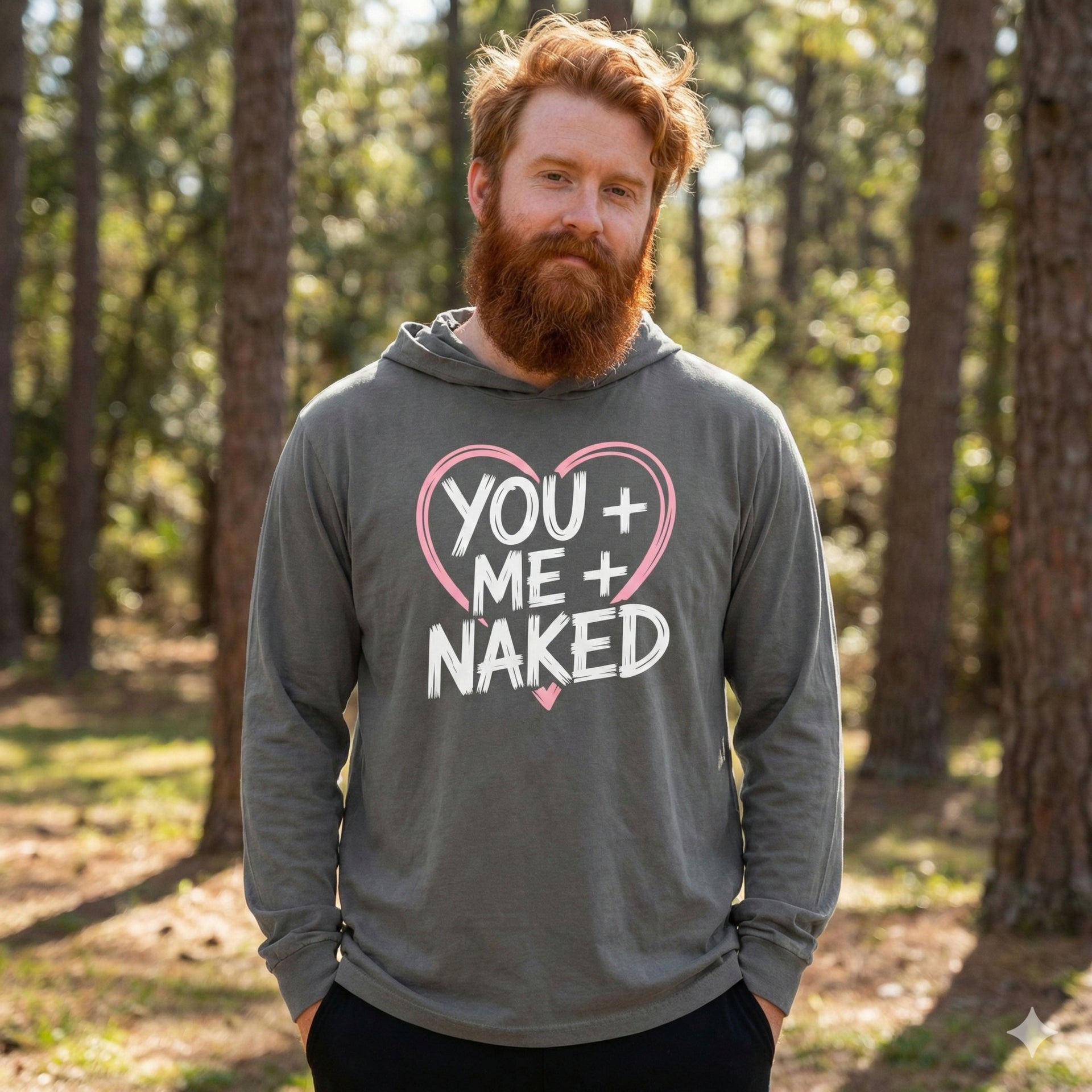 redheaded male model wearing gray featherweight hoodie with the phrase "You + Me + Naked" with a minimalist sketched valentine's heart surrounding the phrase to complete the design
