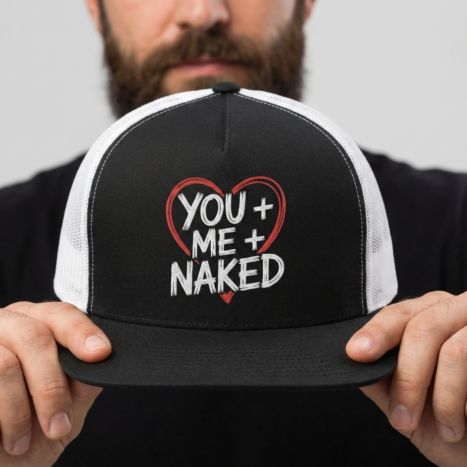 a male model holding a black and white flat bill valentines trucker hat with the phrase "You + Me + Naked" surrounded by a Valentine's Heart